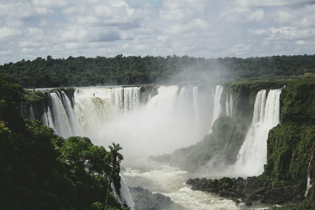 waterfalls under white clouds and blue sky during daytime