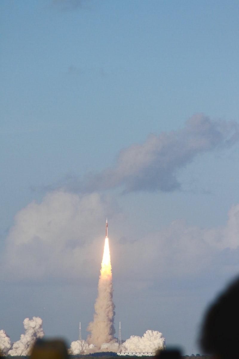 Rocket launching into a cloudy sky with smoke.