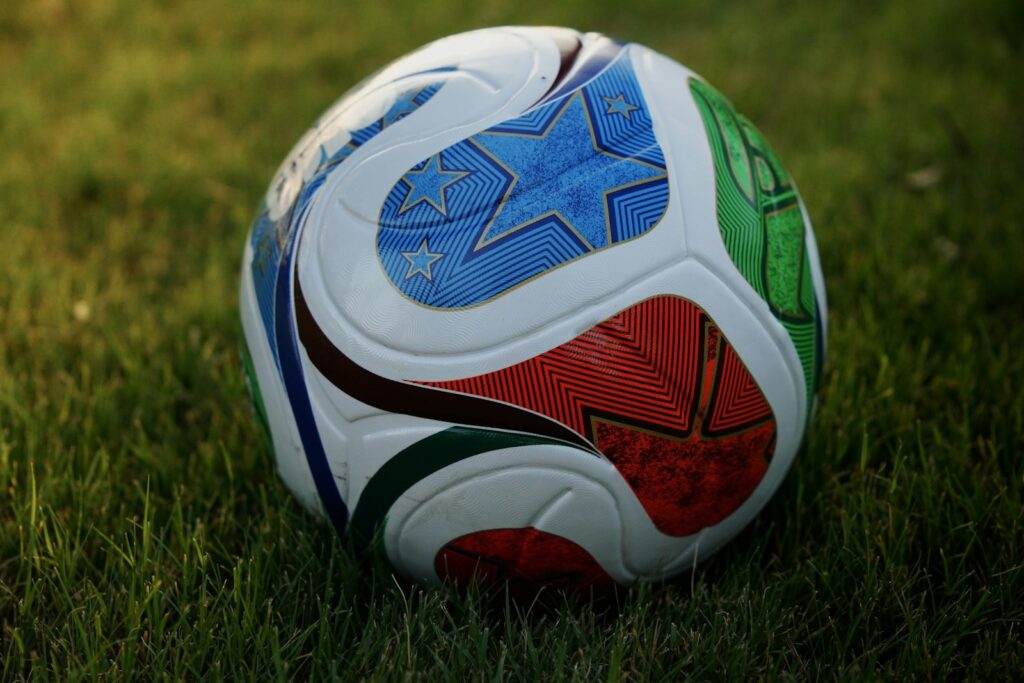 A colorful soccer ball rests on green grass.