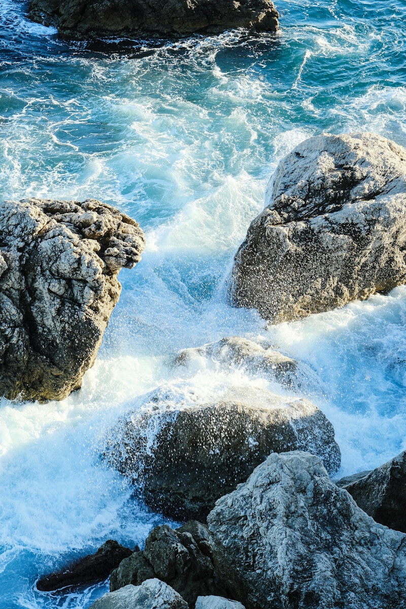 Turquoise ocean waves crash over sunlit rocks.