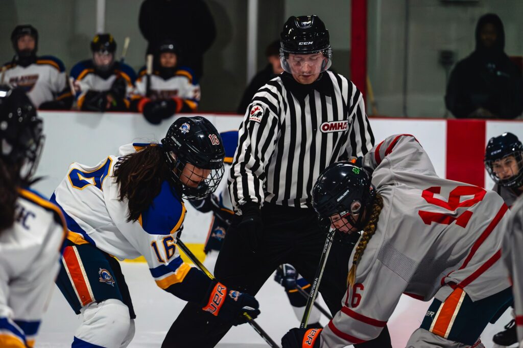 Hockey players face off with referee watching