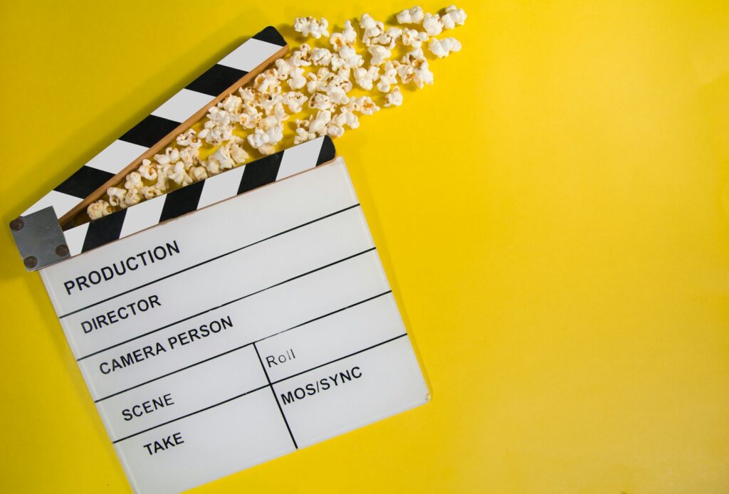 movie clapperboard with popcorn on yellow background