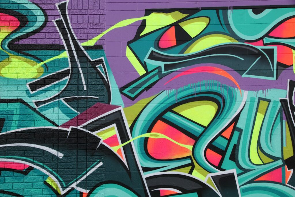 Vibrant graffiti with teal, purple, and neon yellow shapes on a brick wall