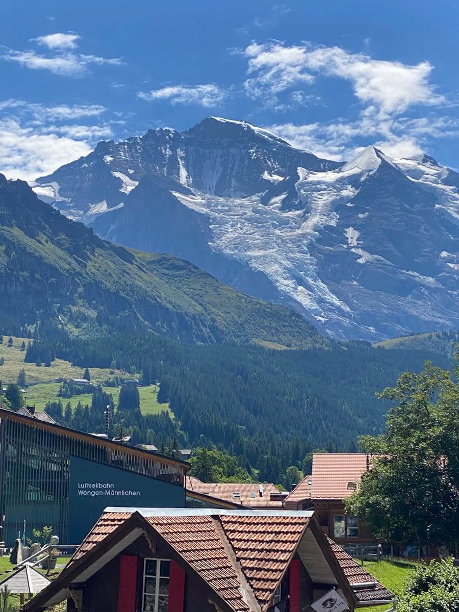 Picturesque village nestled against a stunning mountain backdrop under a clear blue sky.